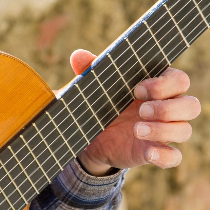 Mano en el mástil de una guitarra clásica durante el curso